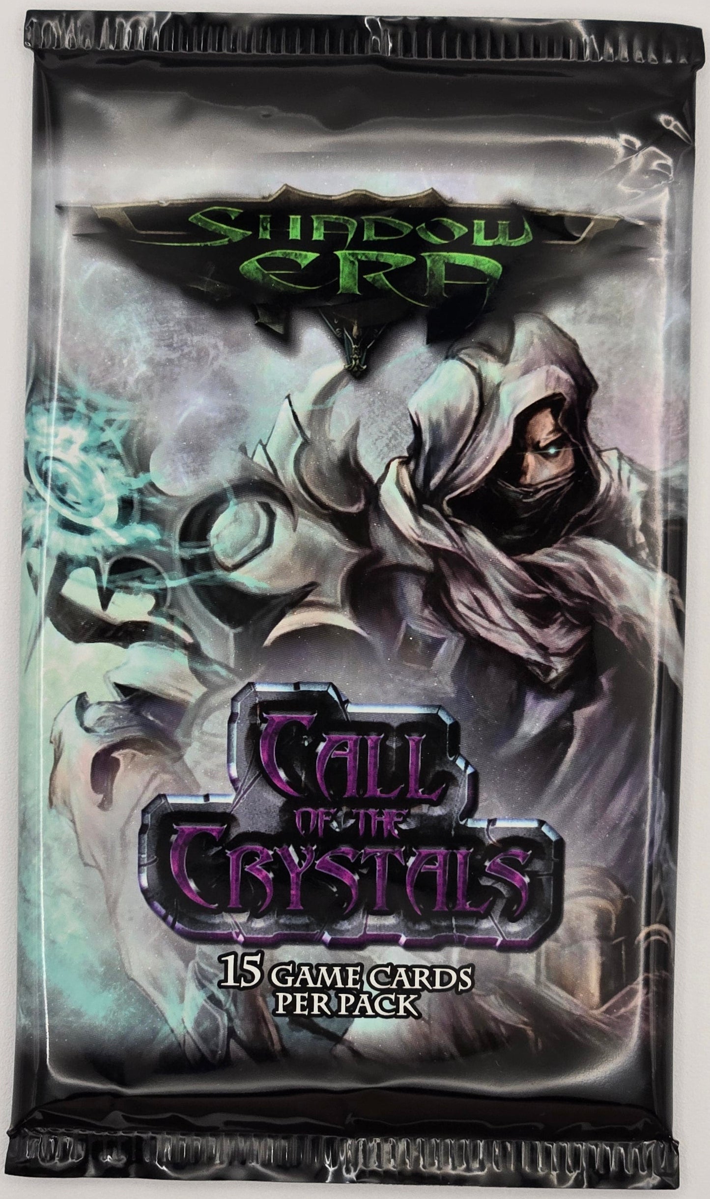 A sealed Call of the Crystals Shadow Card 2012 booster pack featuring artwork of a hooded figure and glowing crystals, photographed against a plain light background.